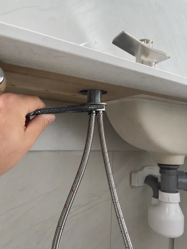 Low profile bathroom faucet installation showing supply line routing and mounting nut position under vanity deck