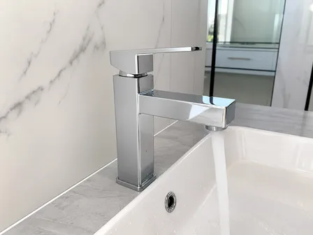 Chrome finish on modern square-body bathroom faucet showing polished flat planes