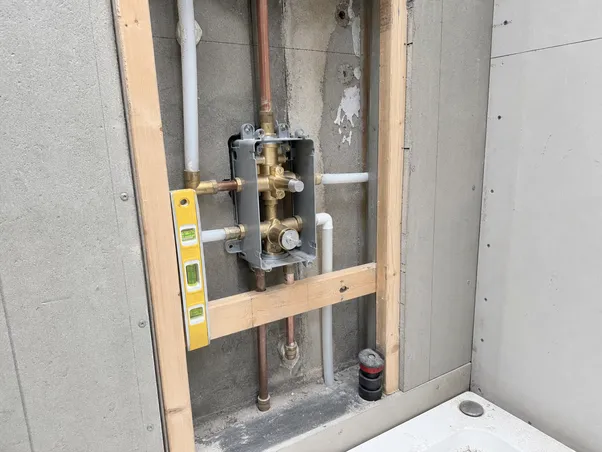 Concealed shower system rough-in installation — valve body positioned in wall cavity before tiling