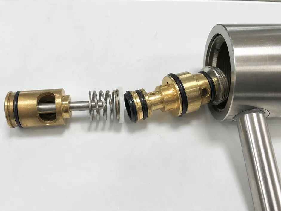Brass diverter valve and stainless steel spring assembly inside a kitchen faucet aerator switch mechanism