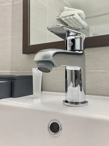 Cache-style aerator installed on hotel bathroom faucet for institutional maintenance program