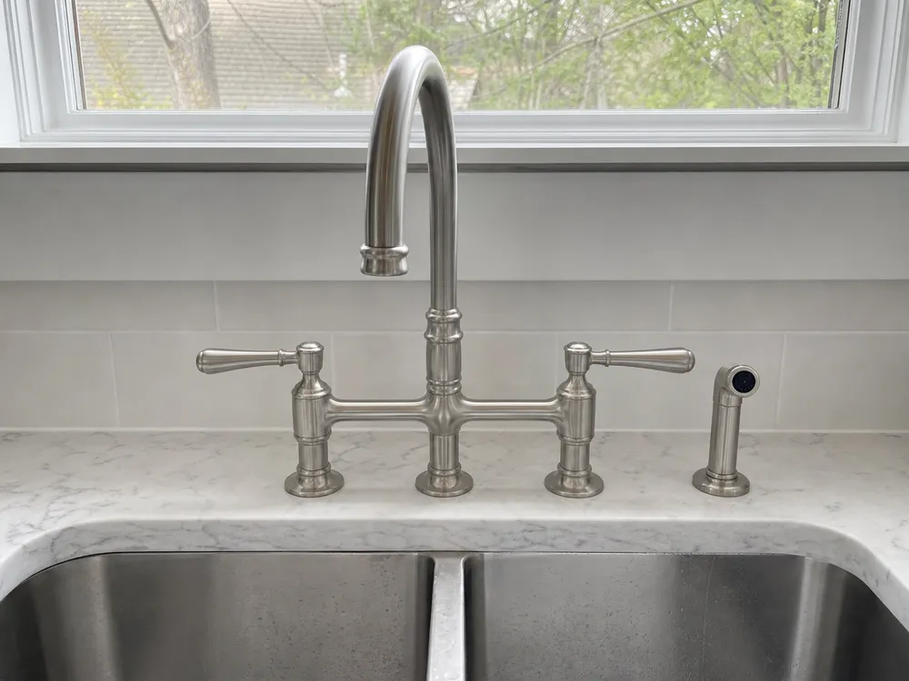 Two-handle bridge brushed nickel kitchen faucet — traditional bridge form with separate hot and cold handles