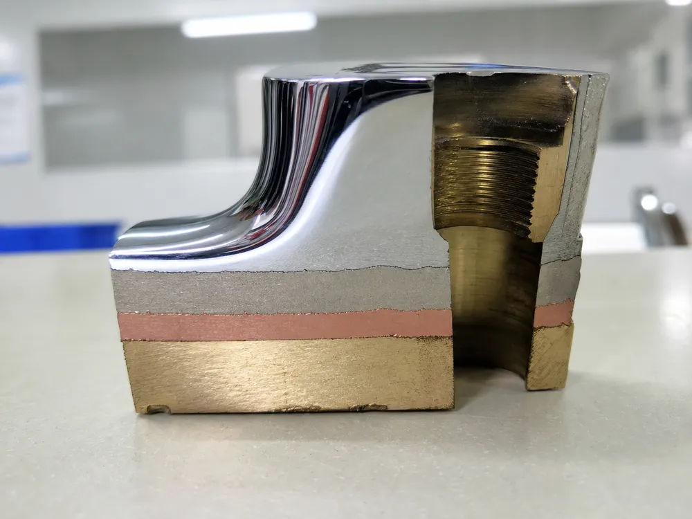Chrome plating layer cross-section showing copper base, nickel mid-coat, and chrome top coat on brass substrate