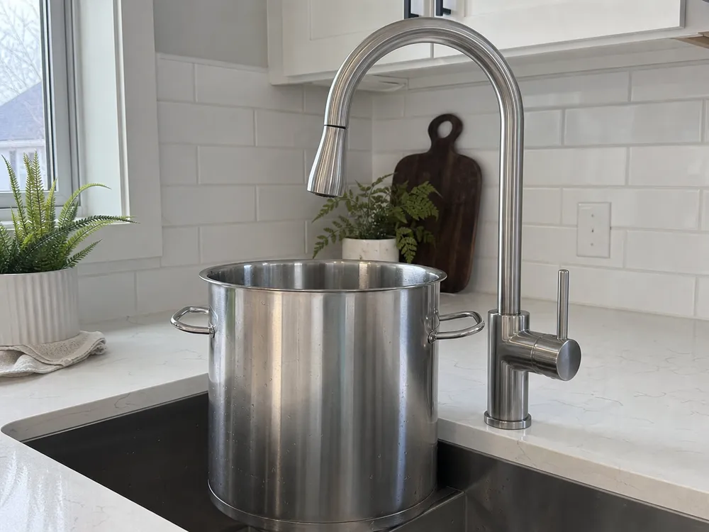 Gooseneck kitchen faucet high-arc spout clearing a large stockpot in a residential kitchen