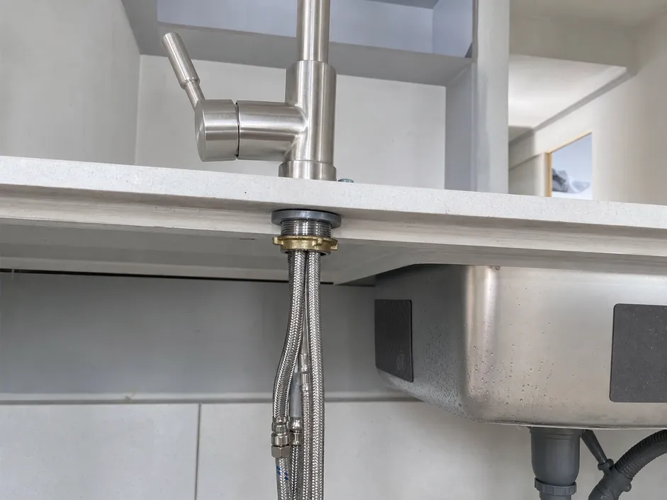 Single handle kitchen faucet installation showing deck hole and braided stainless supply connections