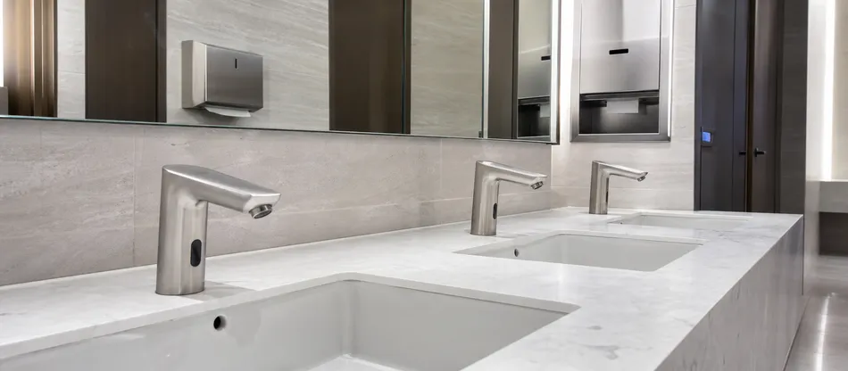 Hotel lobby washroom with brushed stainless sensor faucet installation