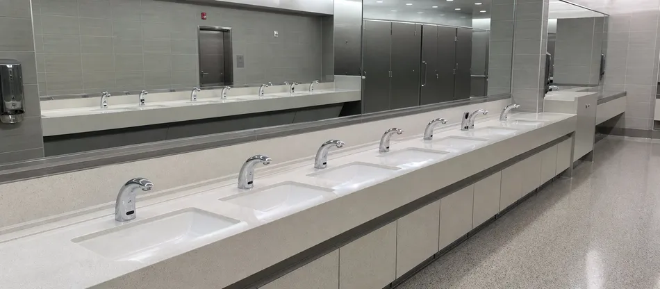 High-traffic airport washroom with sensor faucets installed across multiple basins
