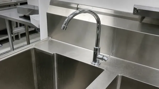 Stainless sink faucet installed in a commercial kitchen food service environment