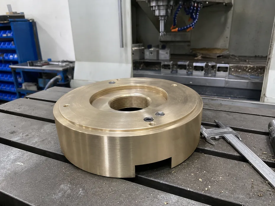 Close-up of freestanding bathtub faucet base casting — precision-machined brass floor plate with CNC-held thread tolerance