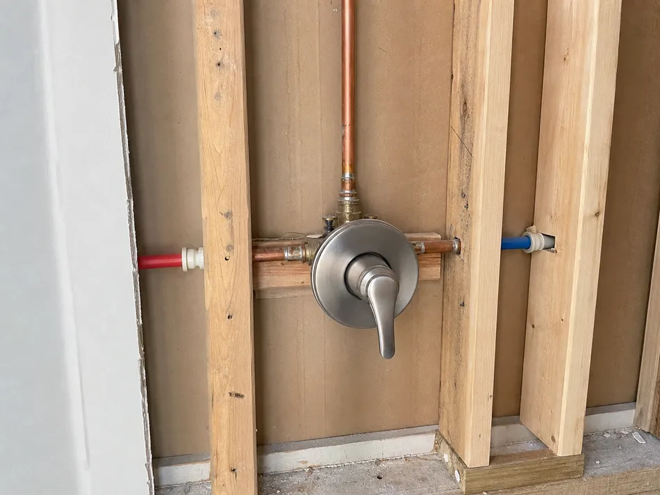 Single handle shower faucet valve body rough-in installation in wall cavity showing trim plate and handle assembly