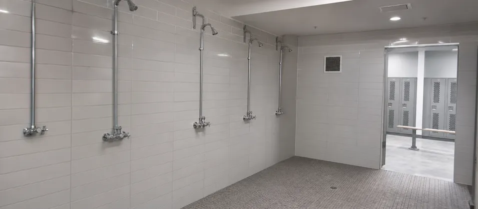 Commercial shower room with exposed wall mount shower valves in institutional facility