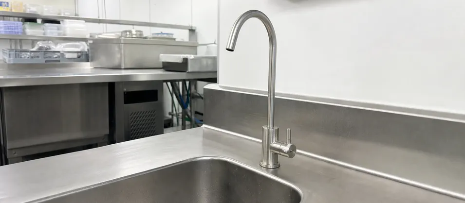 Beverage faucet installed at commercial kitchen prep station for filtered water dispensing