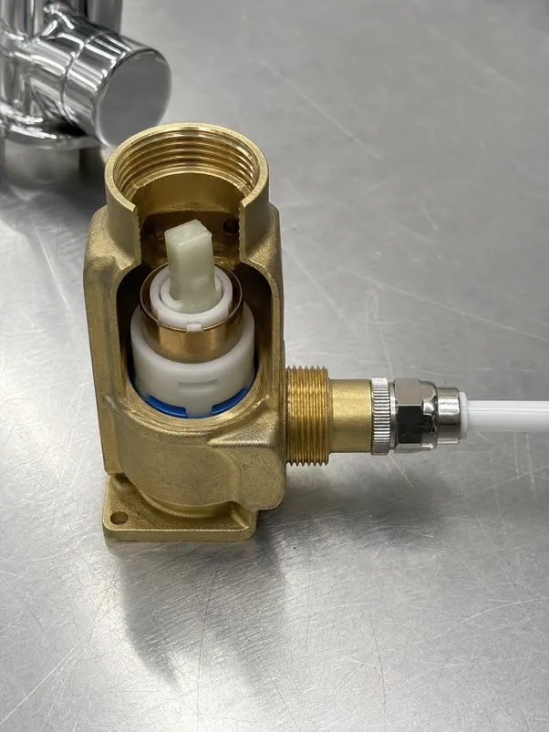 Under sink water filter faucet brass body detail showing ceramic disc cartridge and supply tube connection